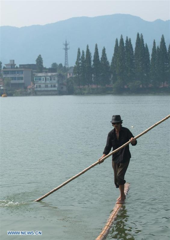 Cidadão de Hangzhou atravessa rio Xin'an com duas canas de bambu