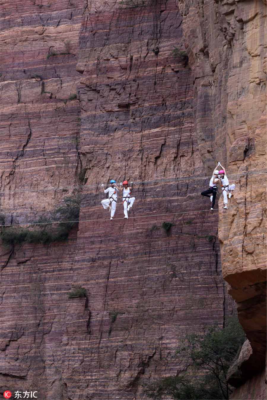 Entusiastas praticam yoga em penhasco