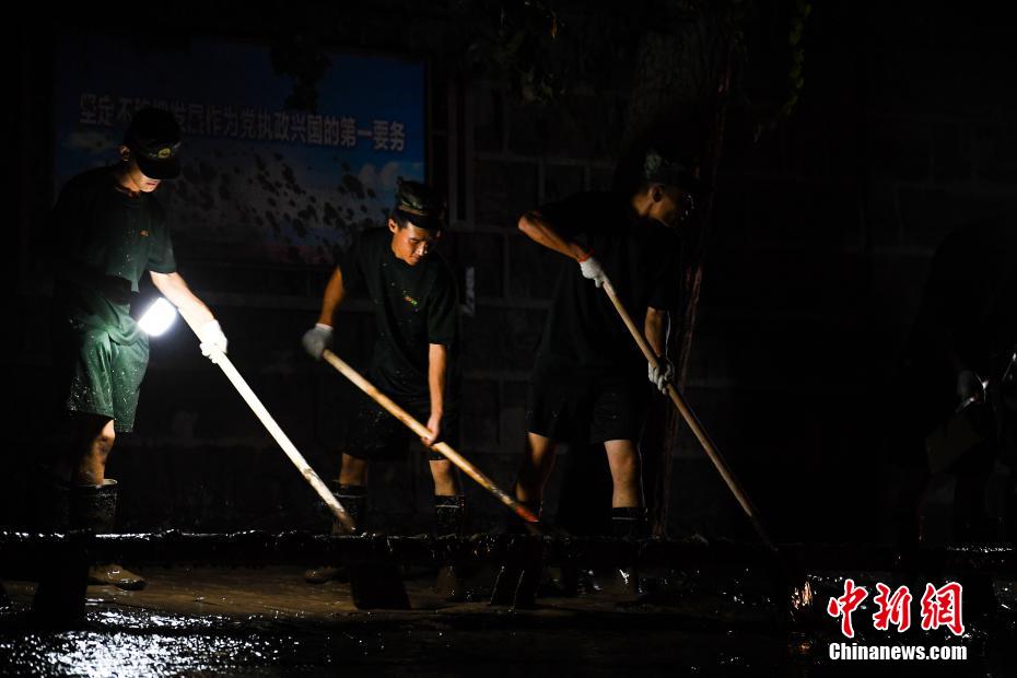 Oficiais e soldados limpam lama depois da inundação em Chongqing