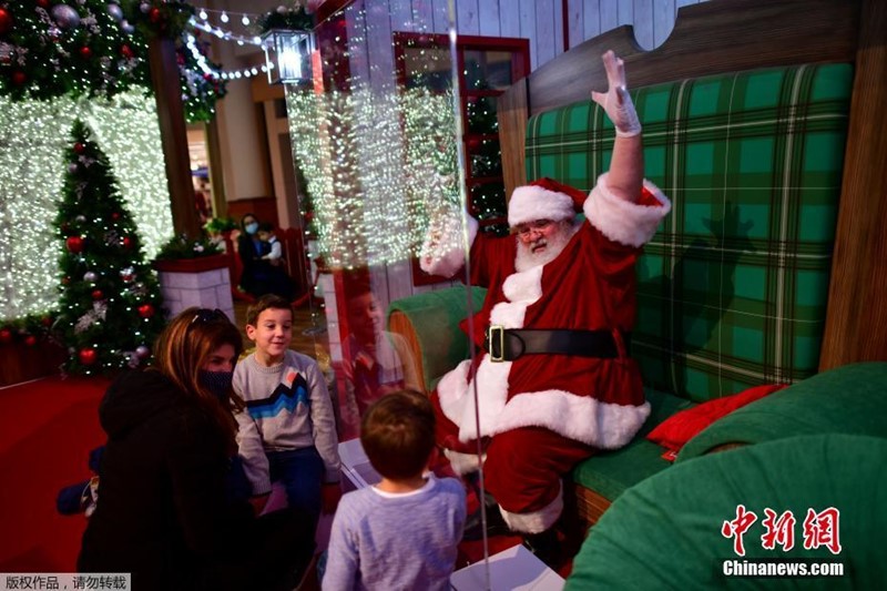 Papai Noel interage com crianças por vidro durante pandemia