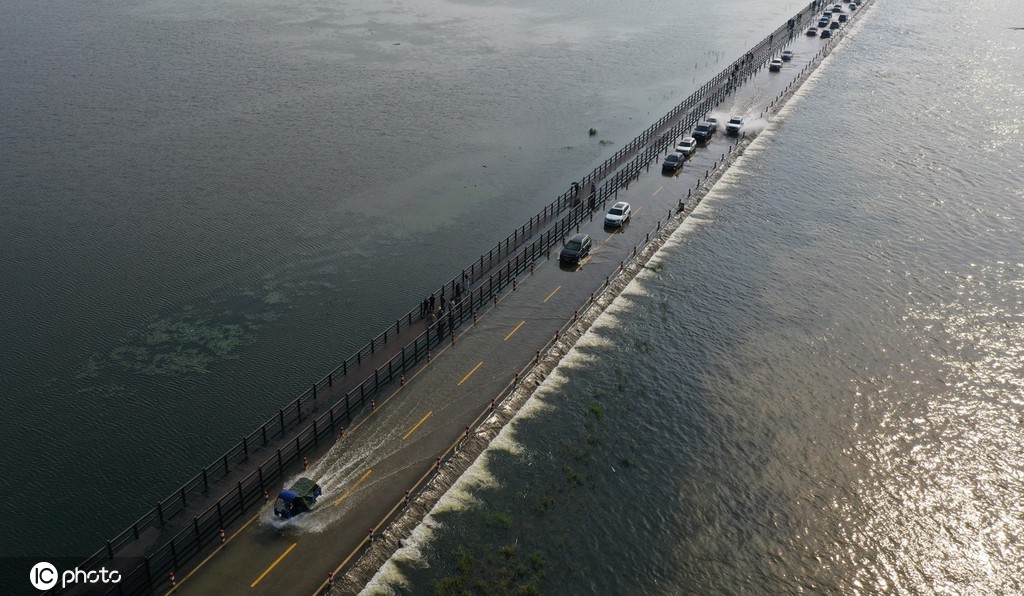 Veículos atravessam estrada inundada