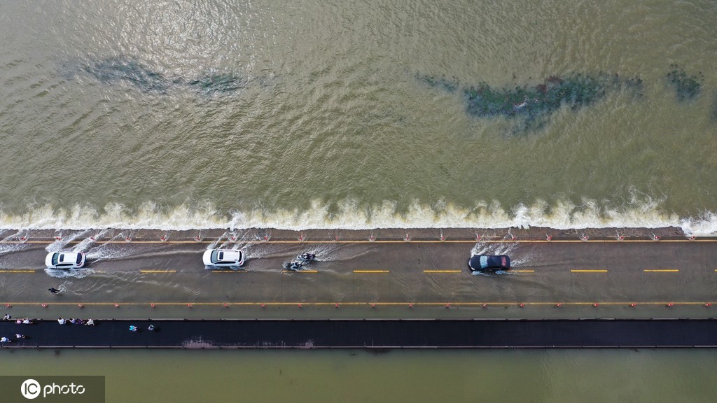 Veículos atravessam estrada inundada