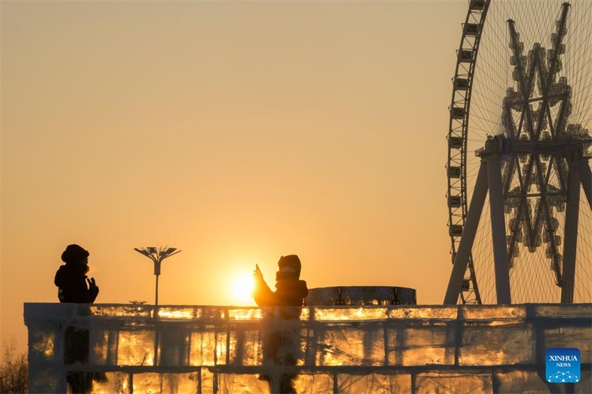 Turistas se divertem ao pôr do sol no Mundo de Gelo e Neve de Harbin, no nordeste da China